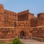 Agra Fort – History, Architecture, Timings, Entry Fees & Travel Guide Majestic view of Agra Fort’s red sandstone walls with tourists entering Amar Singh Gate.
