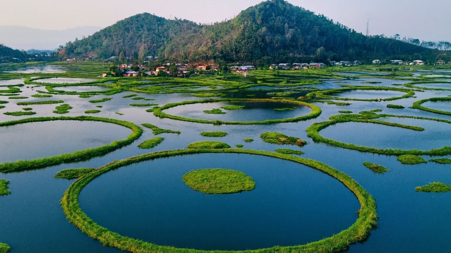 Aerial panorama of Loktak Lake and its floating circular phumdis in Manipur. Bird’s eye view of Loktak Lake with circular green phumdis floating on water.