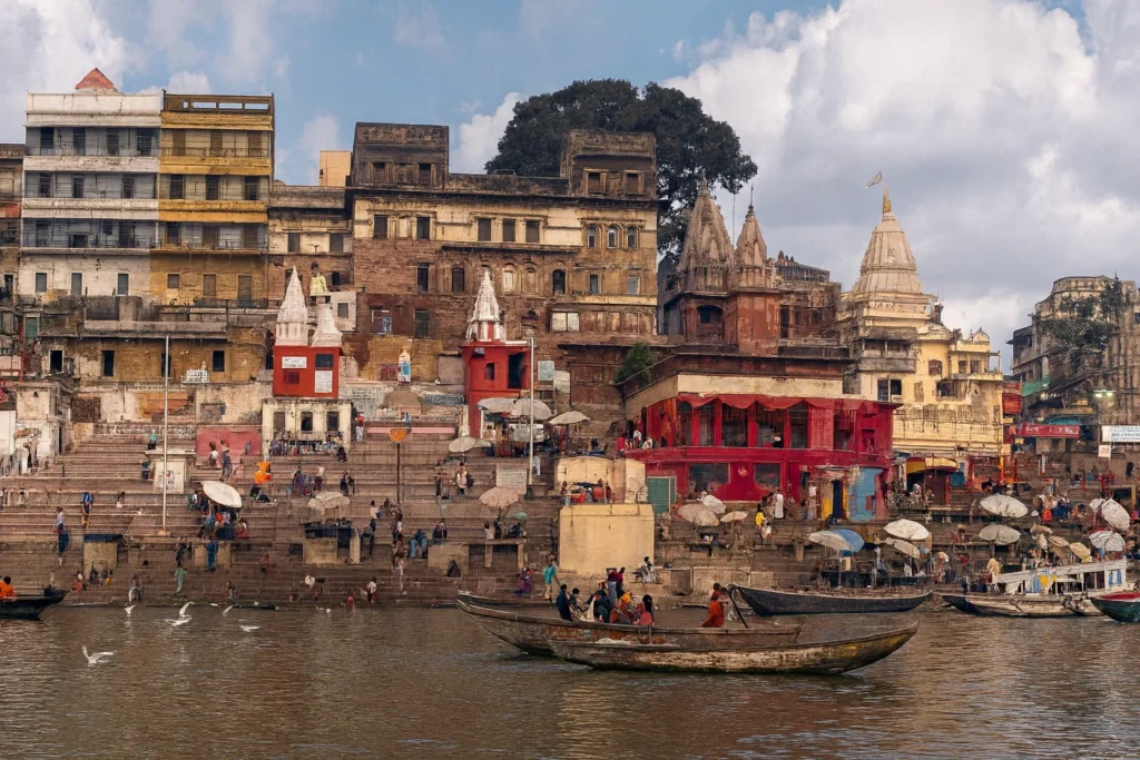 Varanasi Tourism – The Eternal City of Lord Shiva Panoramic view of Varanasi ghats with historic temples, colourful buildings, and boats on the Ganges