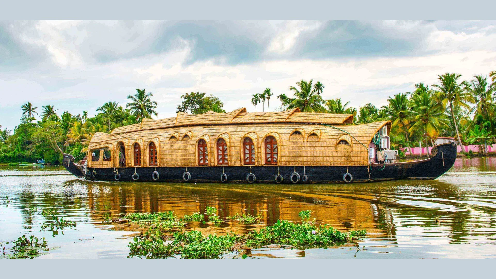 Kerala backwaters — traditional houseboat on palm-fringed lagoon Traditional Kerala houseboat (kettuvallam) cruising the palm-lined backwaters, with reflections on the lagoon.